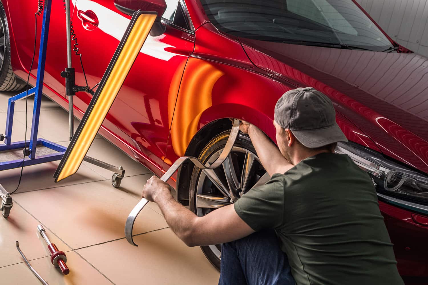 Technician performing paintless dent repair on car fender using specialized tools in Montrose, CO